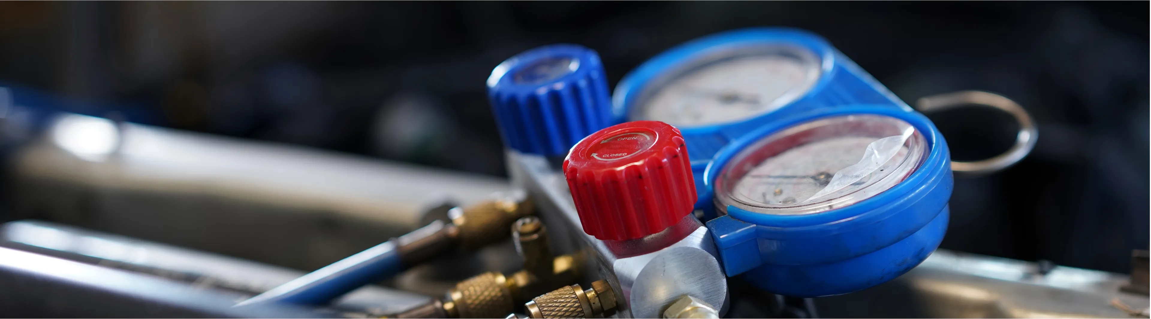 A mechanic checking car AC pressure with manifold gauges.