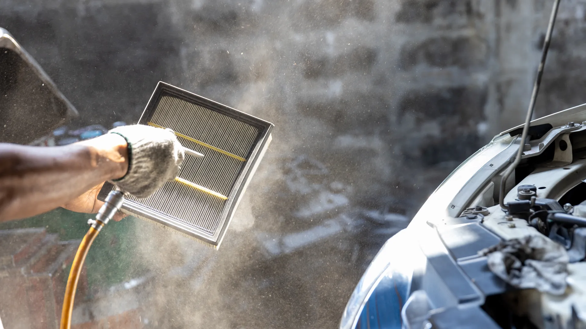a mechanic uses compressed air to clean the engine air filter