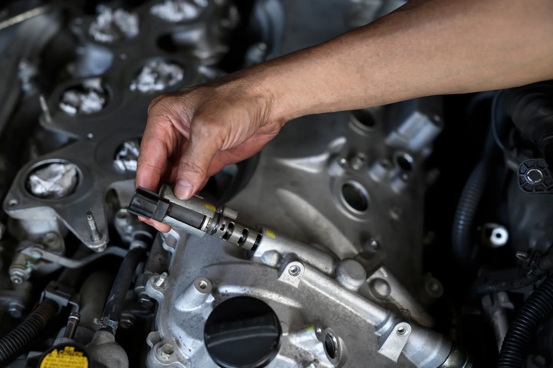 Mechanic replacing VVT solenoid on engine